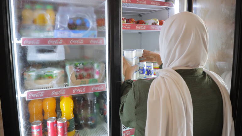 Ameera räumt ein Kühlregal in ihrem Laden ein.