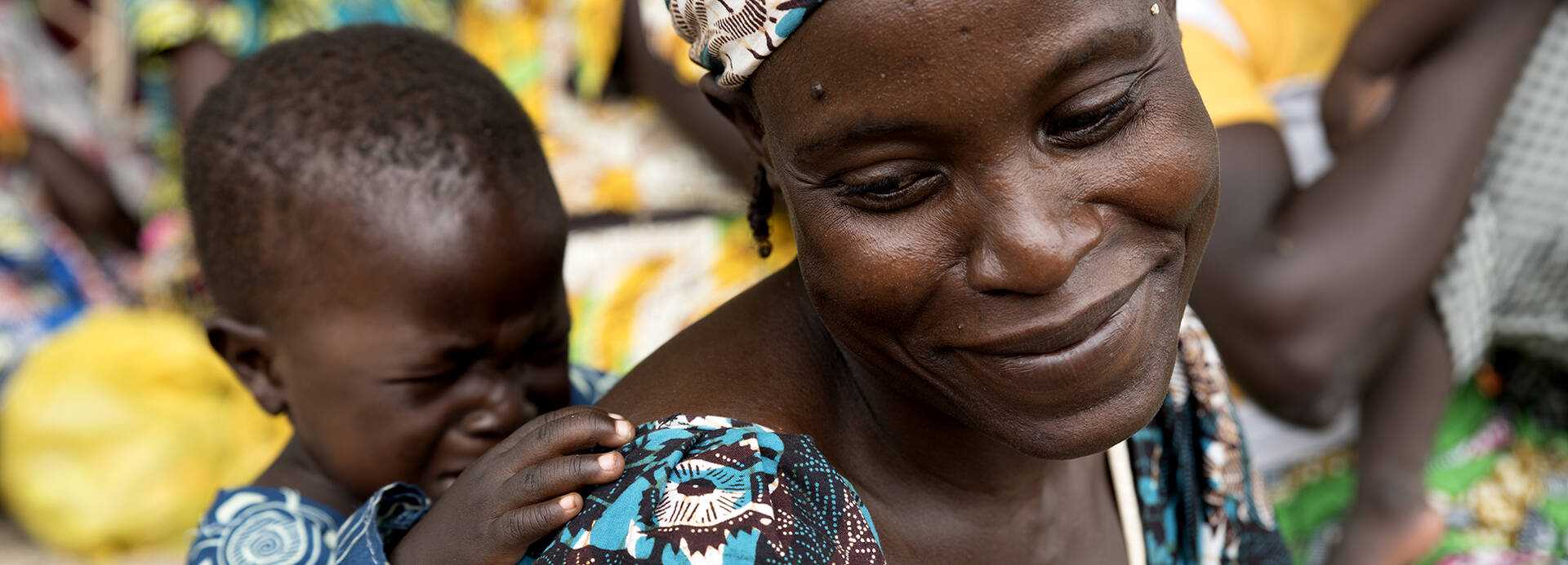 Frau trägt im Kamerun ihr Kind auf dem Rücken.