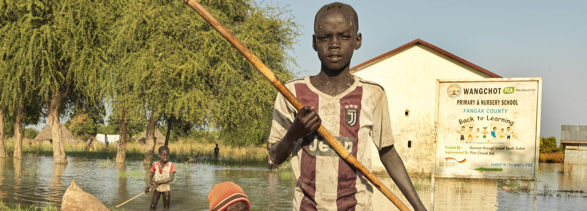 Ein Junge fährt mit einer älteren Frau in einem Baumstamm-Boot durch ein überflutetes Gebiet im Südsudan.