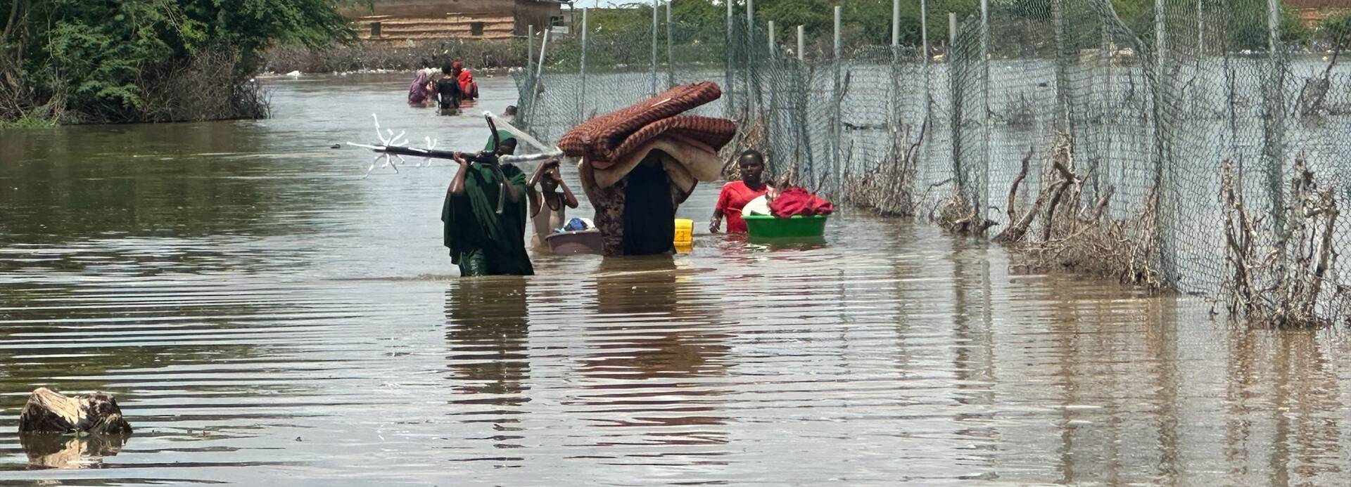Eine Familie aus Somalia versucht, zumindest einen Teil ihrer Habseligkeiten vor den Überflutungen zu retten. Sie laufen durchs hüfthohe Wasser.