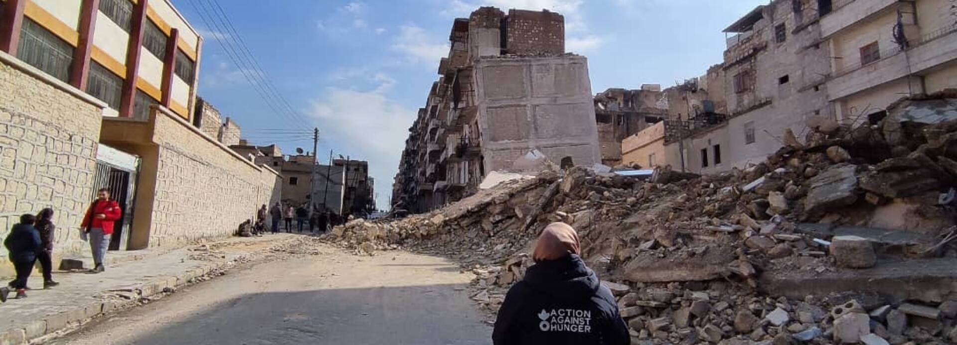 Eine Mitarbeiterin von Aktion gegen den Hunger läuft durch eine vom Krieg zerstörte Straße in Syrien.