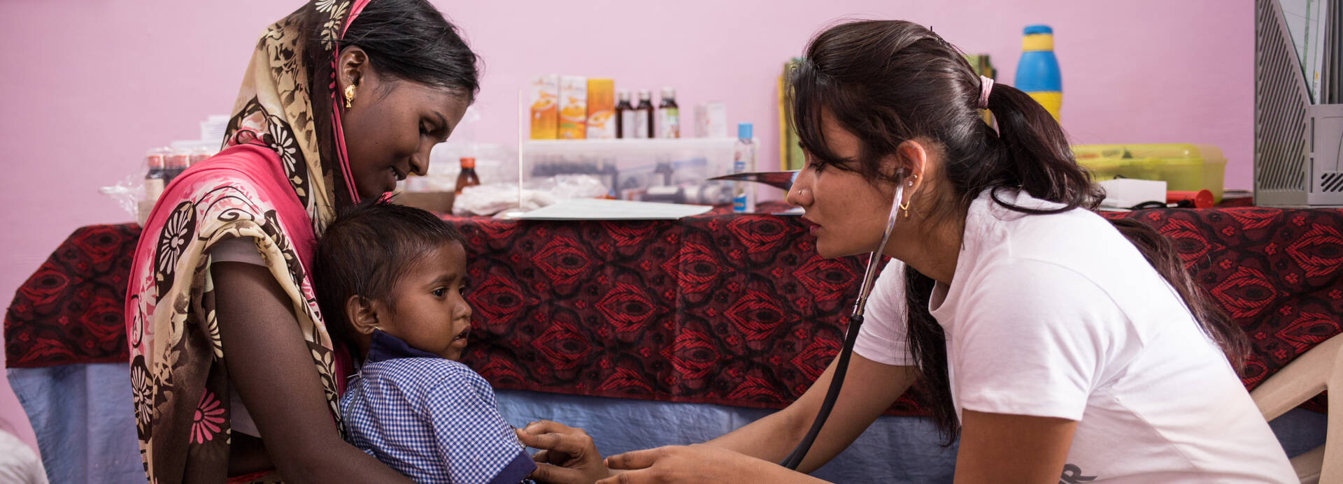 Eine Ärztin in einem Gesundheitszentrum in Indien untersucht ein Kleinkind auf Mangelernährung.