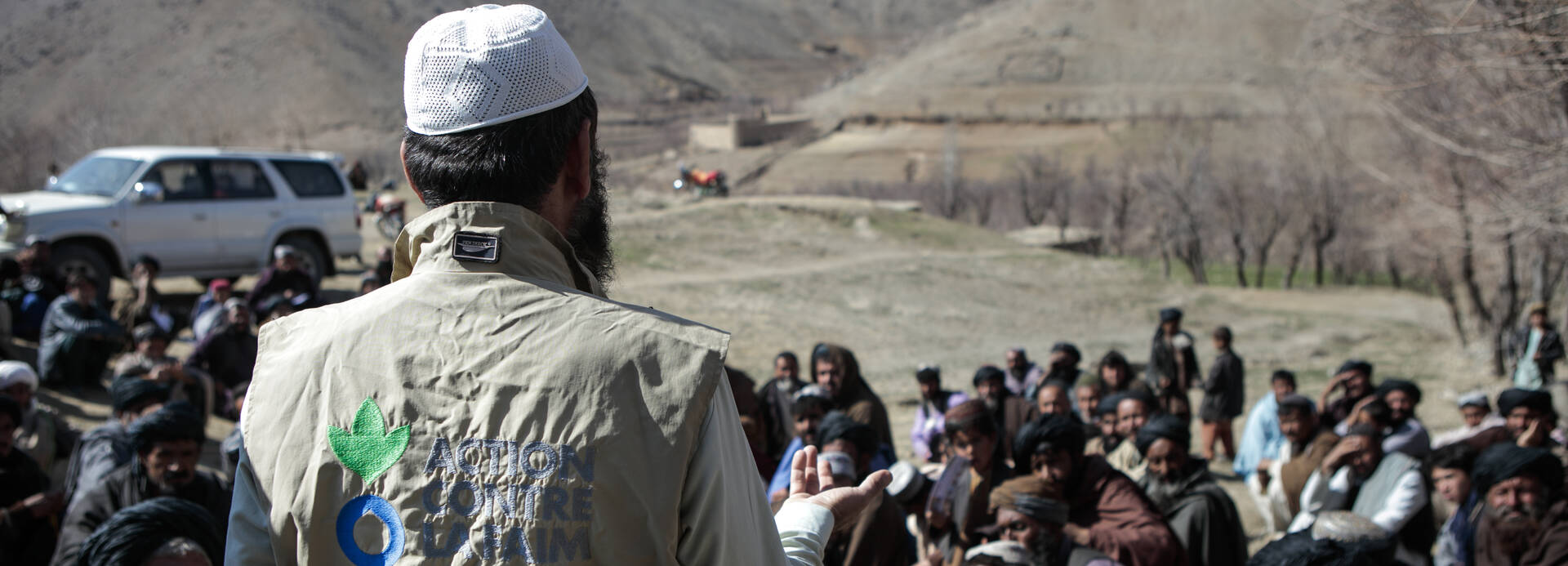 Ein Mitarbeiter von Aktion gegen den Hunger spricht vor einer Menschengruppe in Afghanistan.