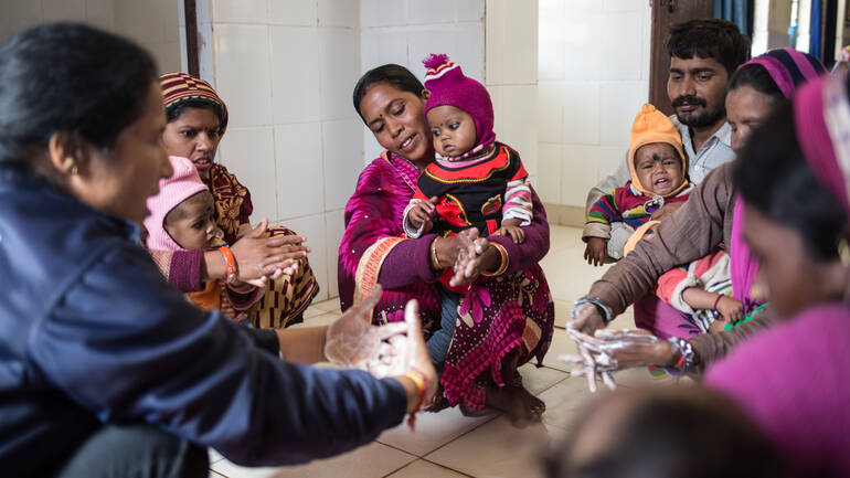 Bhumikas Mutter Sunita lernt in einer Schulung mit anderen Familien, wie korrekte Handhygiene aussieht.