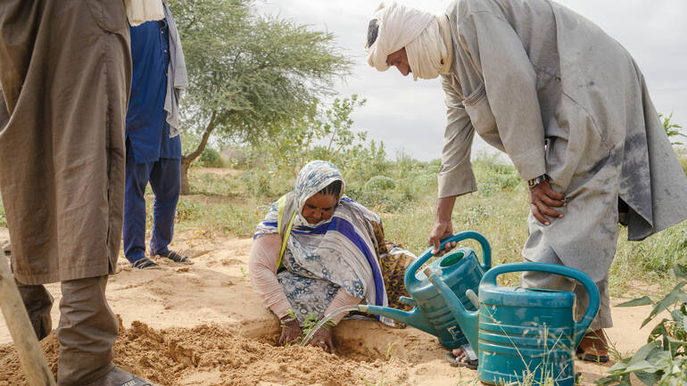 Zwei Personen gießen Wasser in eine Latrine in einem Geflüchtetencamp in Mauretanien.