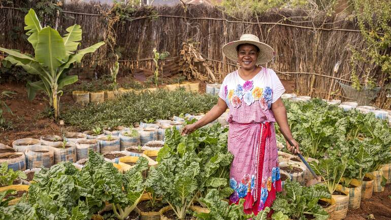 Frau im Garten zeigt ihren Eigenanbau in Tansania