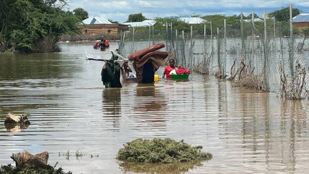 Eine Familie aus Somalia versucht, zumindest einen Teil ihrer Habseligkeiten vor den Überflutungen zu retten. Sie laufen durchs hüfthohe Wasser.