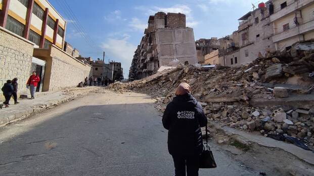 Eine Mitarbeiterin von Aktion gegen den Hunger läuft durch eine vom Krieg zerstörte Straße in Syrien.