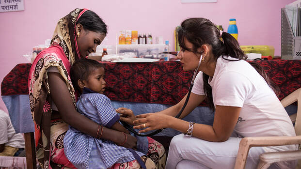 Eine Ärztin in einem Gesundheitszentrum in Indien untersucht ein Kleinkind auf Mangelernährung.