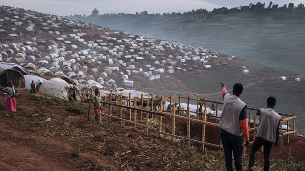 Mitarbeiter von Aktion gegen den Hunger stehen am Rande eines Geflüchtetencamps in der Demokratischen Republik Kongo