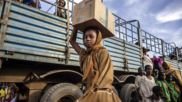 Ein Mädchen aus dem Sudan trägt einen Karton auf dem Kopf bei der Flucht in den Südsudan.