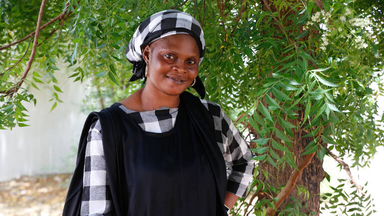 Dié Niang steht vor einem Baum in ihrer Heimat im Senegal