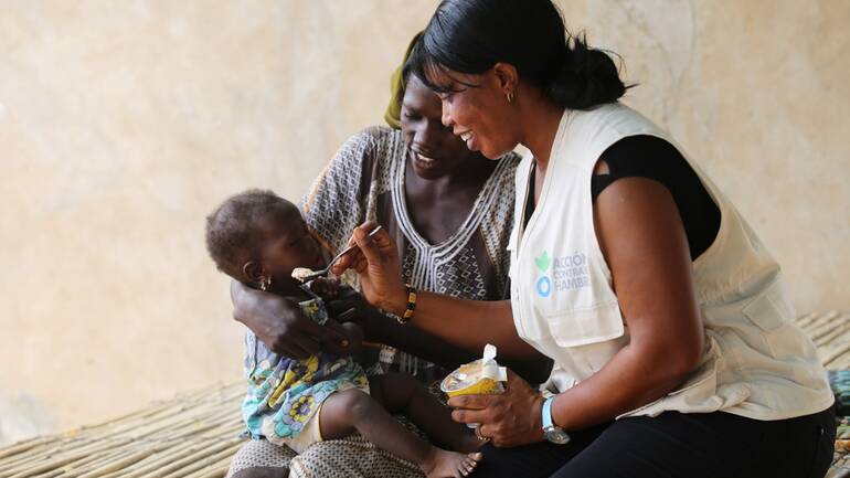Mitarbeiterin von Aktion gegen den Hunger hilft Mutter und Kind Mitarbeiterin von Aktion gegen den Hunger hilft Mutter und Kind