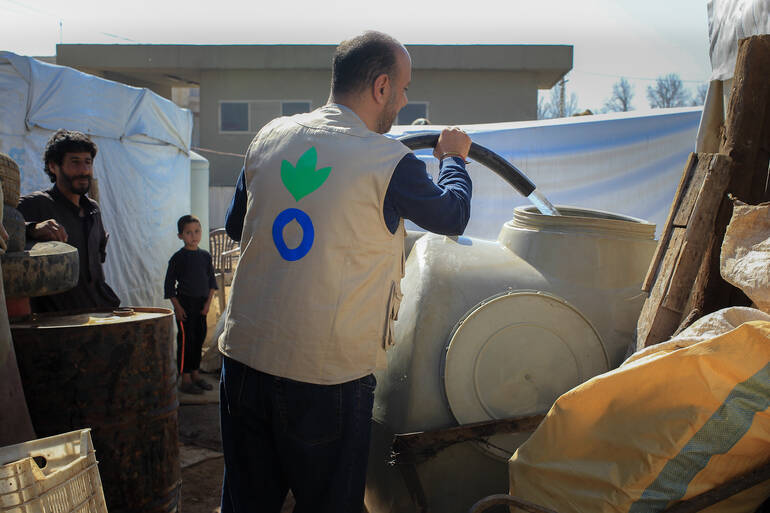 Helfer von Aktion gegen den Hunger füllt Wasserbehälter Helfer von Aktion gegen den Hunger füllt Wasserbehälter