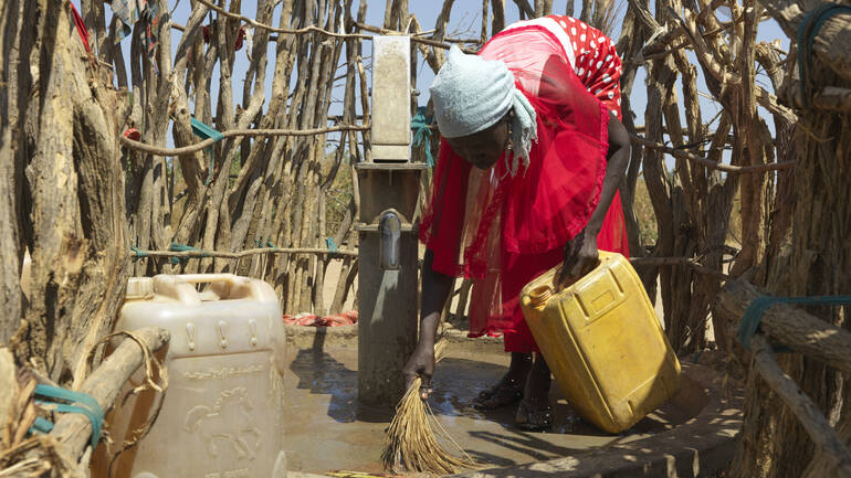 Frau pflegt Brunnen im Südsudan