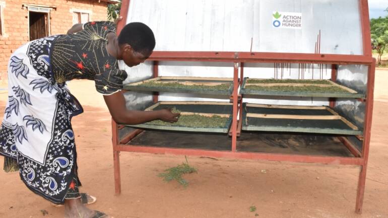 Frau aus Tansania trocknet ihre Ernte im Solartrockner