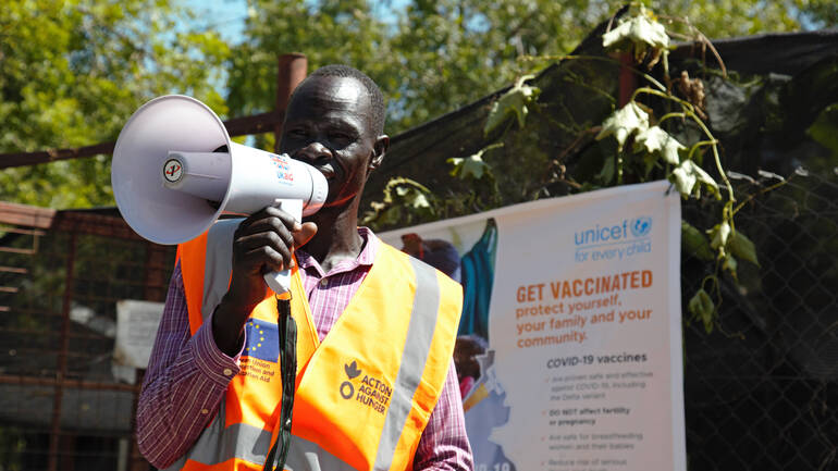 Ein Mitarbeiter von Aktion gegen den Hunger ruft mit einem Megafon zum Impfen im Südsudan auf.