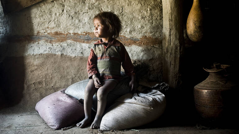 Ein kleines Kind sitzt in Nepal auf Säcken mit Nahrungsmitteln