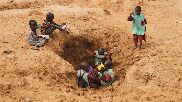 Sechs Kinder sind in einer der trockendsten Gegenden Kenias auf der Suche nach Wasser in einem fast ausgetrockneten Wasserloch