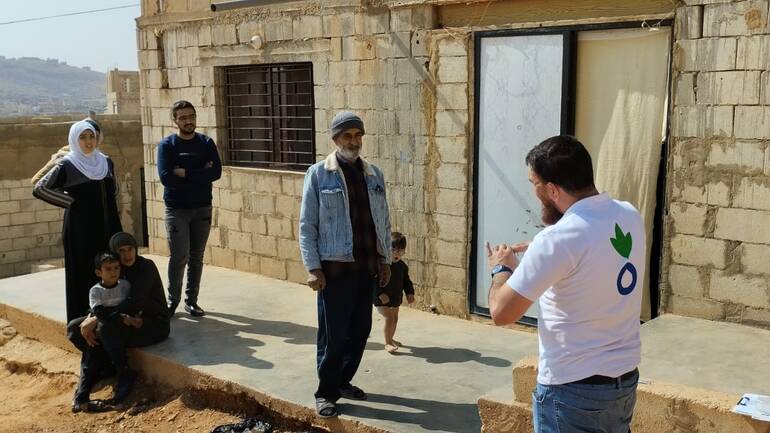 Ein Mitarbeiter von Aktion gegen den Hunger erklärt einer Familie aus dem Libanon, wie sie sich vor Cholera schützen können.