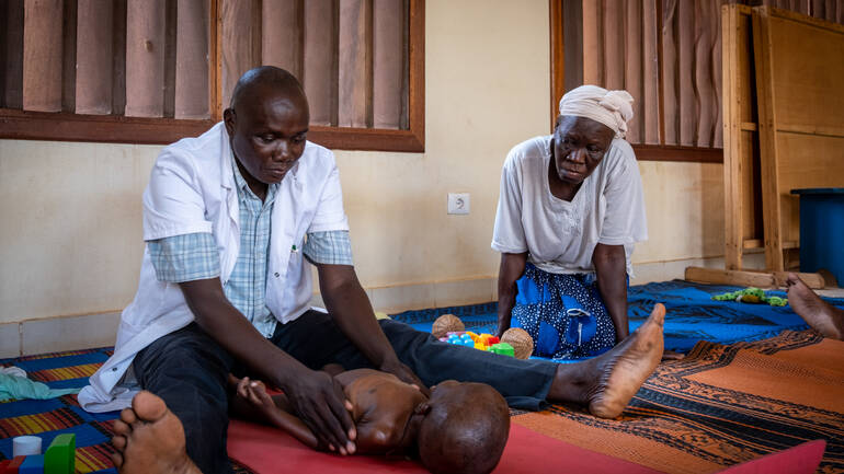 Ein Arzt und eine Ärztin aus dem Rehabilitationszentrum in Bangui in der Zentralafrikanischen Republik behandeln ein Kind, das unter den Folgen frühkindlicher Mangelernährung leidet, mithilfe von phsiotherapeutischen Maßnahmen. Ein Arzt und eine Ärztin aus dem Rehabilitationszentrum in Bangui in der Zentralafrikanischen Republik behandeln ein Kind, das unter den Folgen frühkindlicher Mangelernährung leidet, mithilfe von phsiotherapeutischen Maßnahmen.
