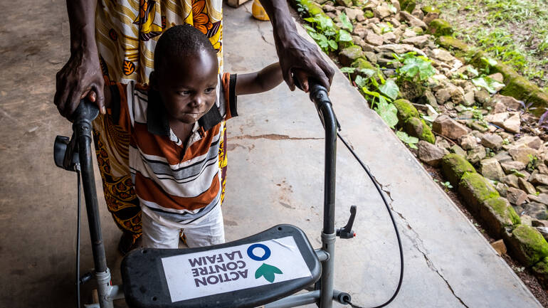 Dieubéni schafft mithilfe eines Rollators von Aktion gegen den Hunger und der Unterstützung seiner Großmutter schon erste Schritte über den Gehweg im Innenhof des Rehazentrums. Dieubéni schafft mithilfe eines Rollators von Aktion gegen den Hunger und der Unterstützung seiner Großmutter schon erste Schritte über den Gehweg im Innenhof des Rehazentrums.