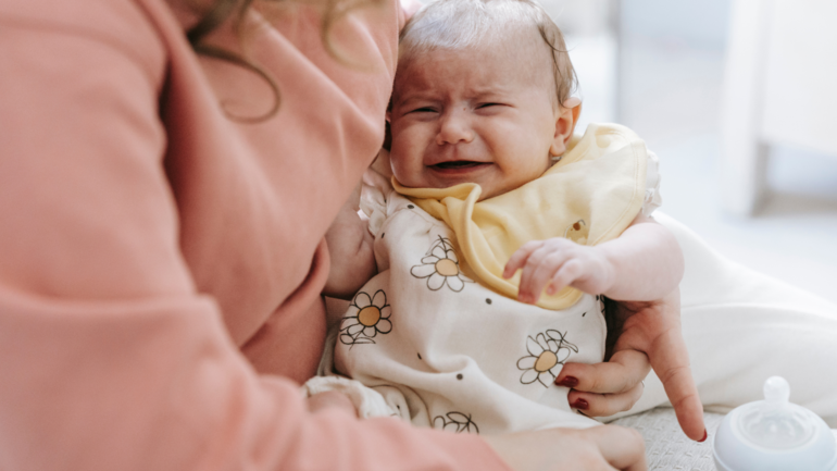 Eine Frau hält ein weinendes Baby in den Armen Eine Frau hält ein weinendes Baby in den Armen