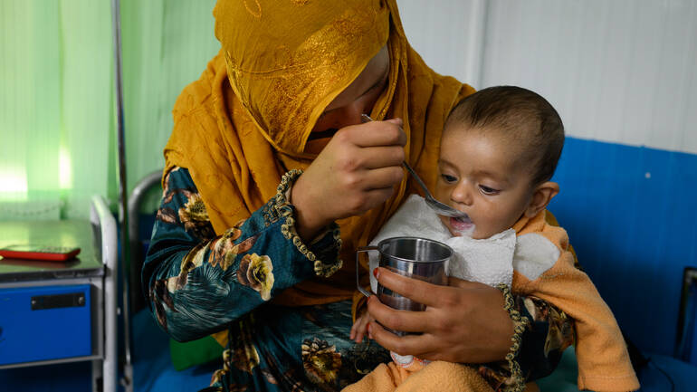 Eine Mutter füttert ihr mangelernährtes Kleinkind mit therapeutischer Milch in der Klinik in Kabul.