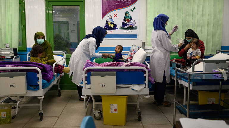 Drei Betten mit mangelernährten Kindern und ihren Müttern, zwei Ärztinnen behandeln zwei der Kinder