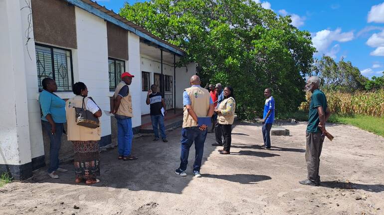 Mary und das Team von Seeds of Hope stehen vor einem Haus in Senanga Mary und das Team von Seeds of Hope stehen vor einem Haus in Senanga