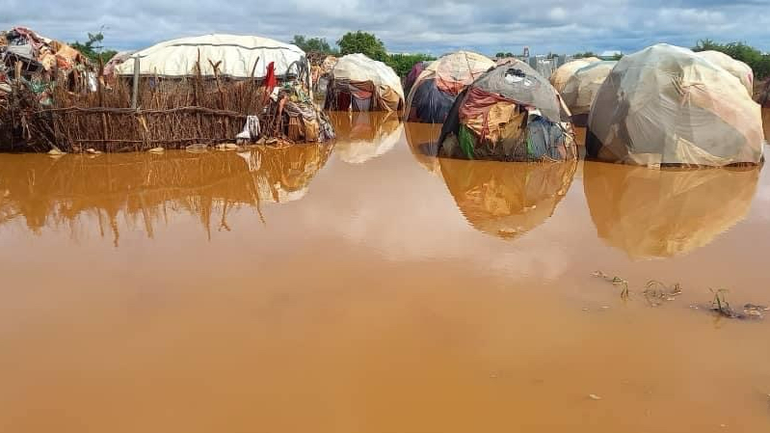 Ein Geflüchtetenlager steht vollständig unter Wasser, das durch die sandigen Böden braun eingefärbt ist.