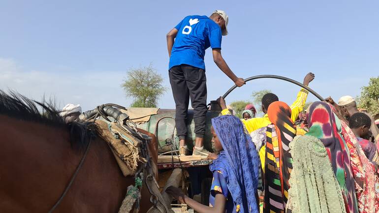 Ein Mitarbeiter von Aktion gegen den Hunger beim Verteilen von sauberem Wasser an geflüchtete Menschen aus dem Sudan im Tschad. Ein Mitarbeiter von Aktion gegen den Hunger beim Verteilen von sauberem Wasser an geflüchtete Menschen aus dem Sudan im Tschad.
