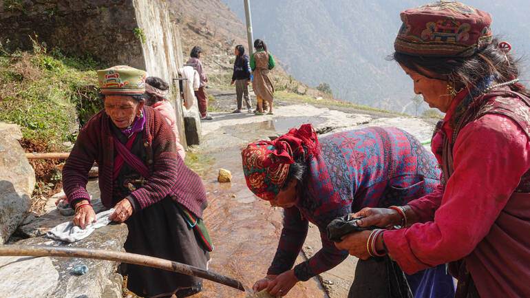 Frauen stehen an einem Brunnen im Dorf in Nepal