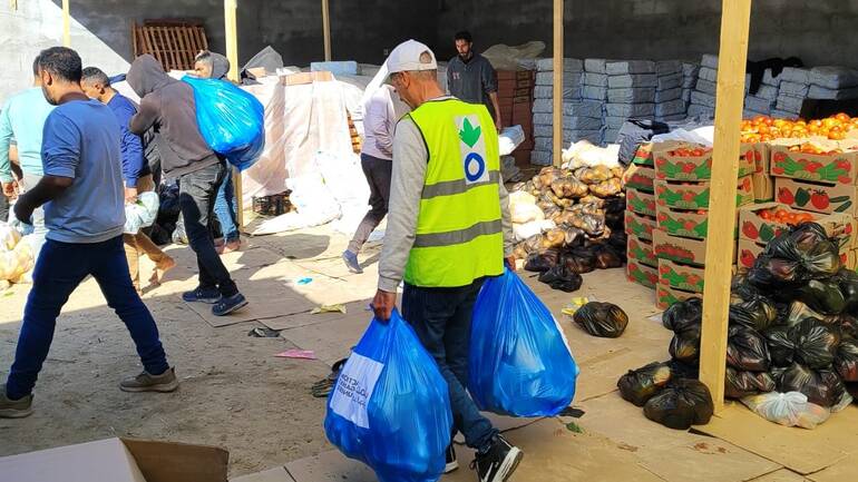Ein Mitarbeiter von Aktion gegen den Hunger trägt Tüten aus einem Lebensmittellager zusammen mit anderen Helfenden in Rafah im Süden Gazas.