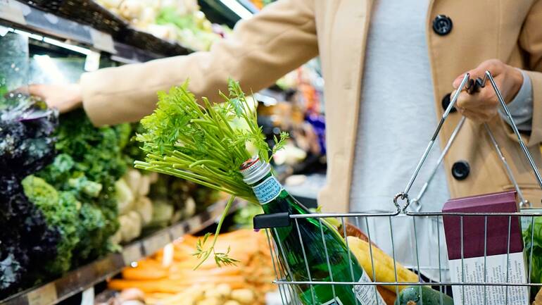 Eine Person steht mit Einkaufskorb vor dem Gemüseregal in einem Supermarkt. Eine Person steht mit Einkaufskorb vor dem Gemüseregal in einem Supermarkt.