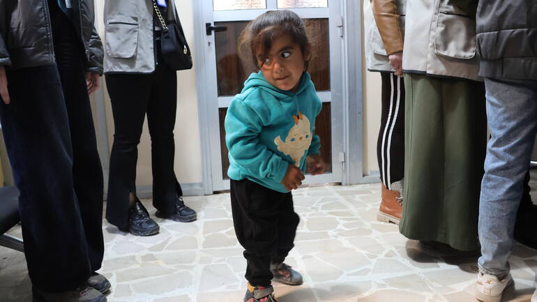 Yasmin geht stolz zwischen den Erwachsenen im Gesundheitszentrum.