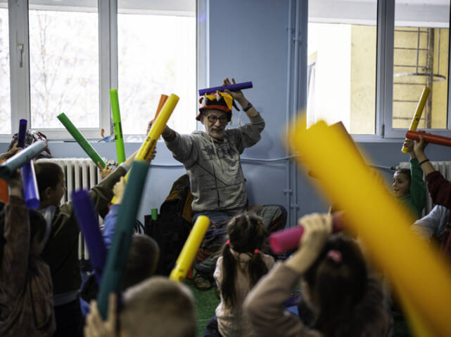 Musiktherapie mit geflüchteten Kindern aus der Ukraine Ein Mitarbeiter macht zusammen mit einer Gruppe Kinder Musik.