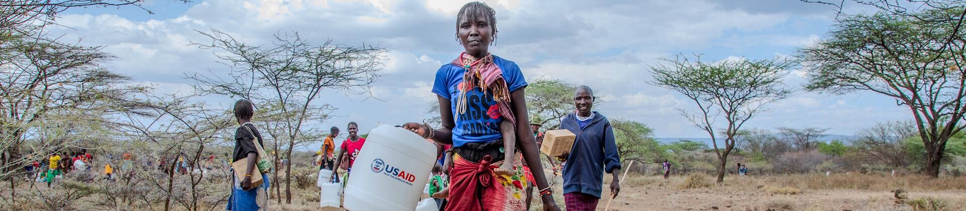 Eine Frau trägt einen Wasserkanister mit der Aufschrift "USAID". Eine Frau trägt einen Wasserkanister mit der Aufschrift "USAID".