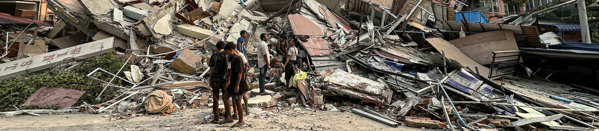 Ein schweres Erdbeben der Stärke 7,7 erschütterte am Morgen des 28.3.2025 Myanmar. Kurz darauf ereignete sich ein Nachbeben der Stärke 6,4, das die bereits entstandenen Schäden noch verschlimmerte. Menschen stehen an den Trümmern eines eingestürzten Gebäudes in Mandalay, in Myanmar, nach einem heftigen Erdbeben.