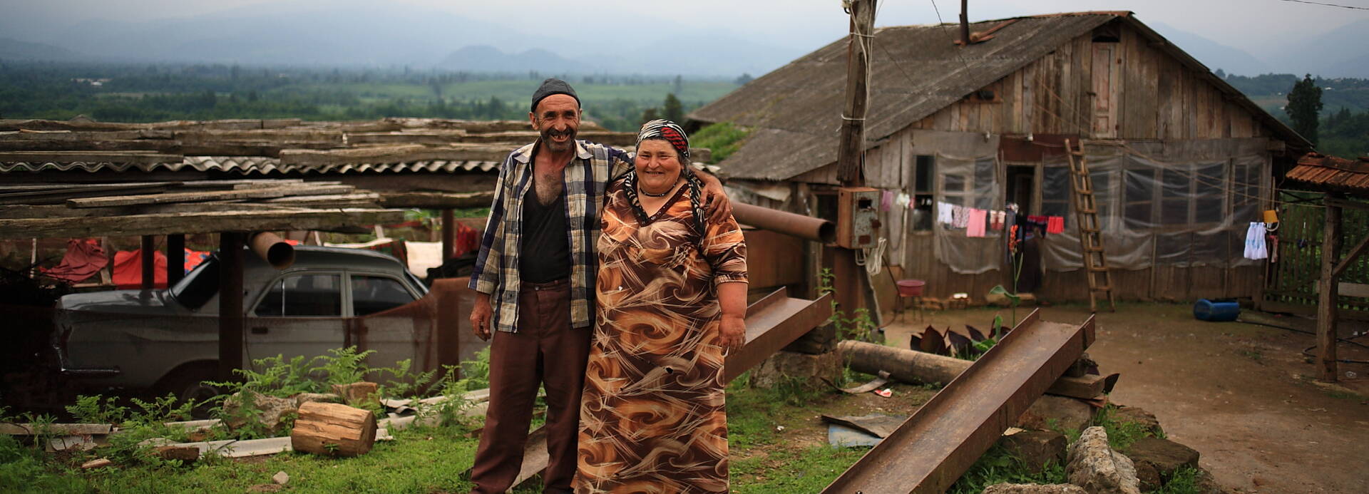 Ein Ehepaar in Georgien steht vor ihrer Hütte.