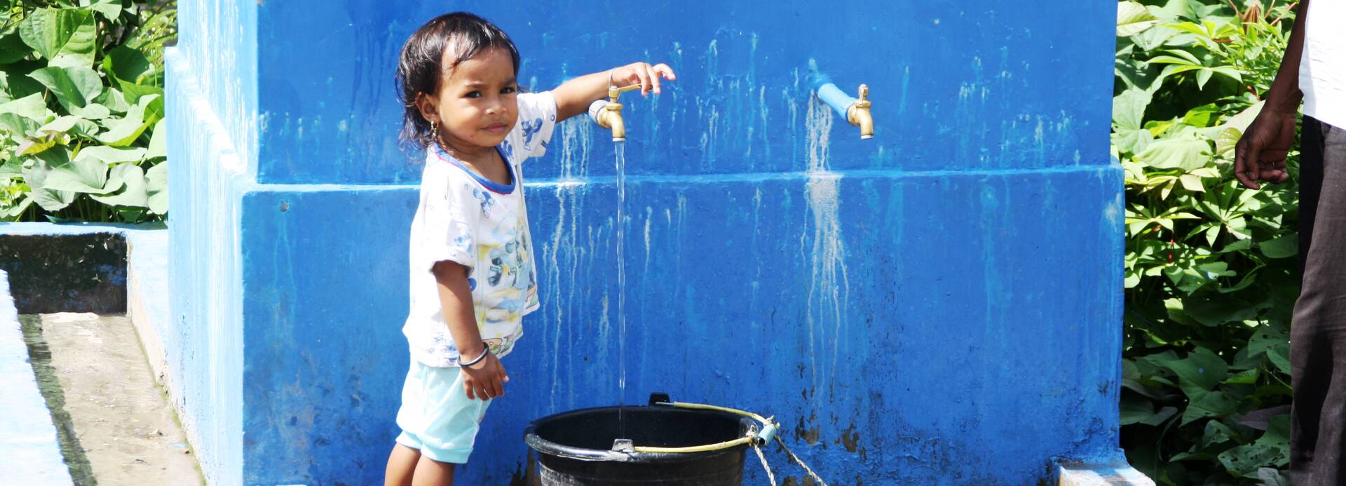 Kind in Indonesien lässt Wasser in einen Eimer ein.