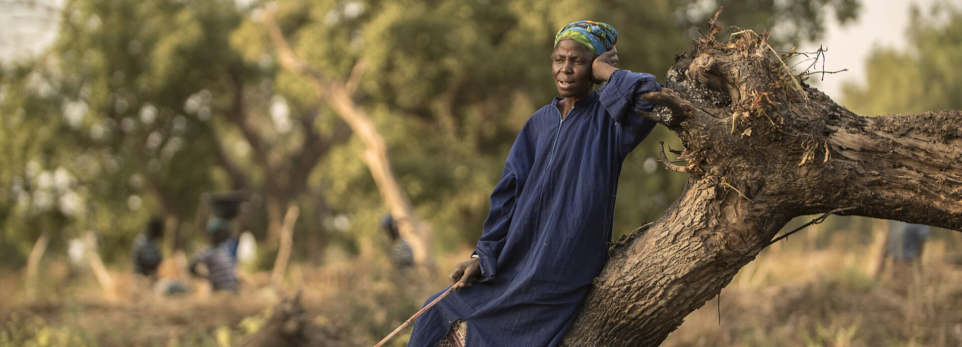Frau in Burkina Faso leht sich an einen Baum.