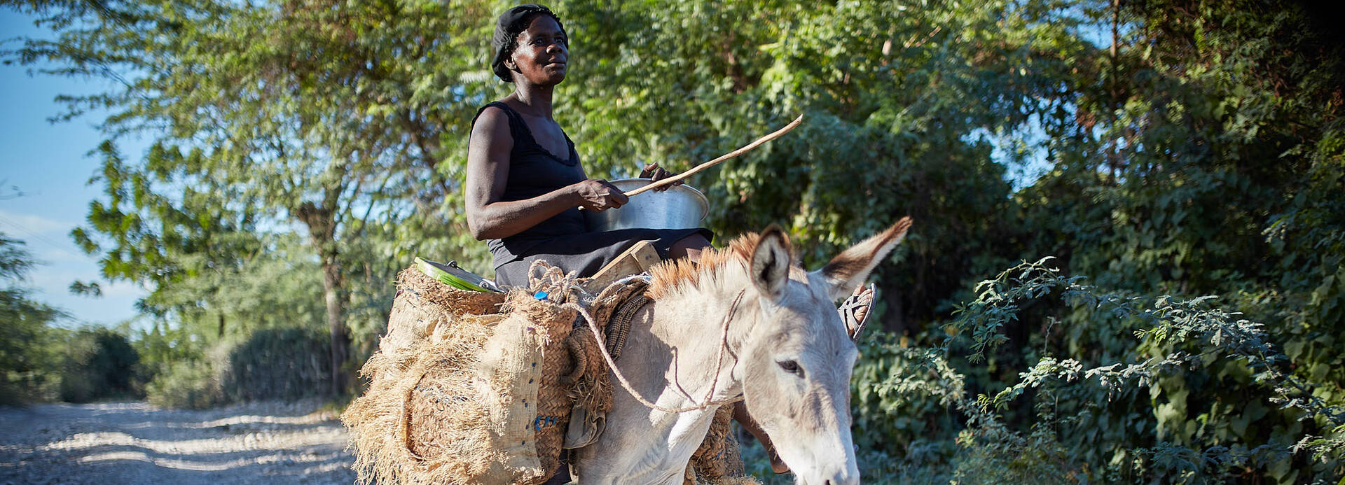 Frau reitet auf einem Esel in Haiti.