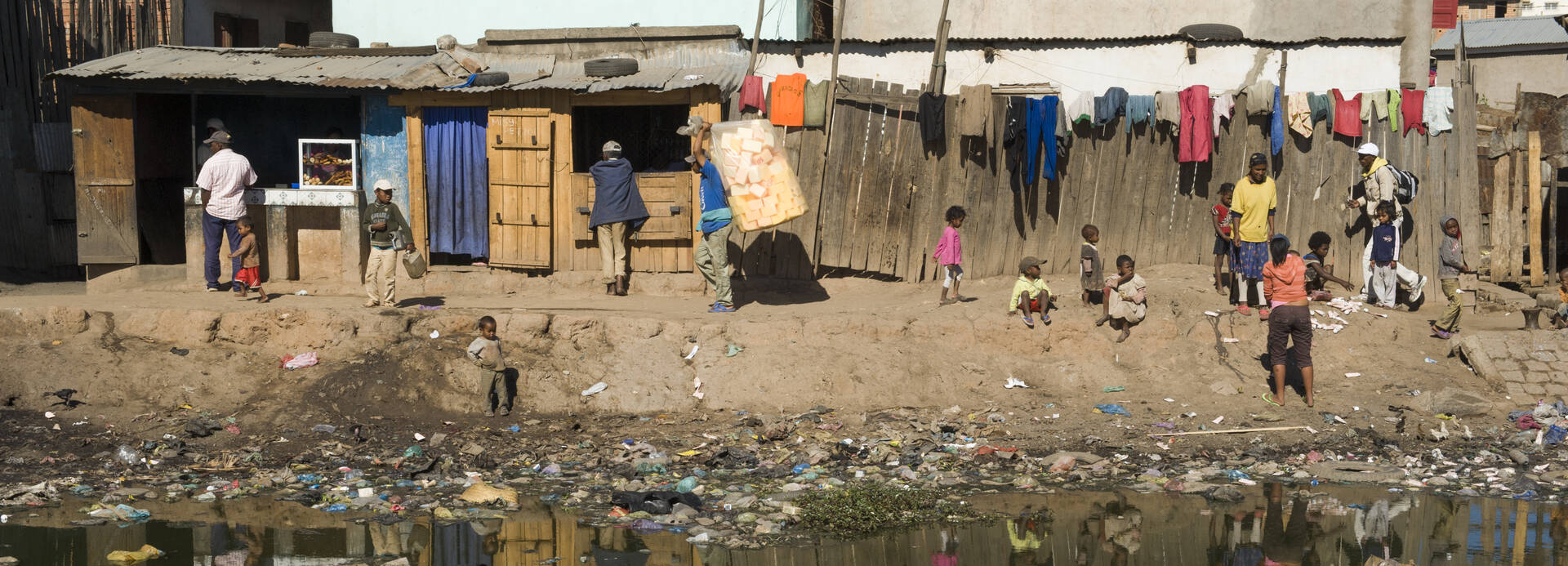 Menschen in Madagaskar an vermülltem Fluss.