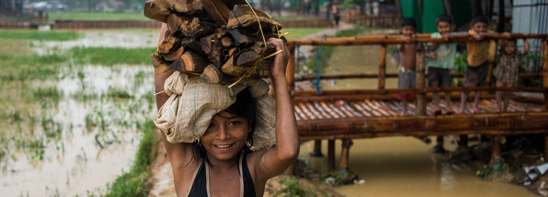Kind in Myanmar trägt einen Stapel Holz.