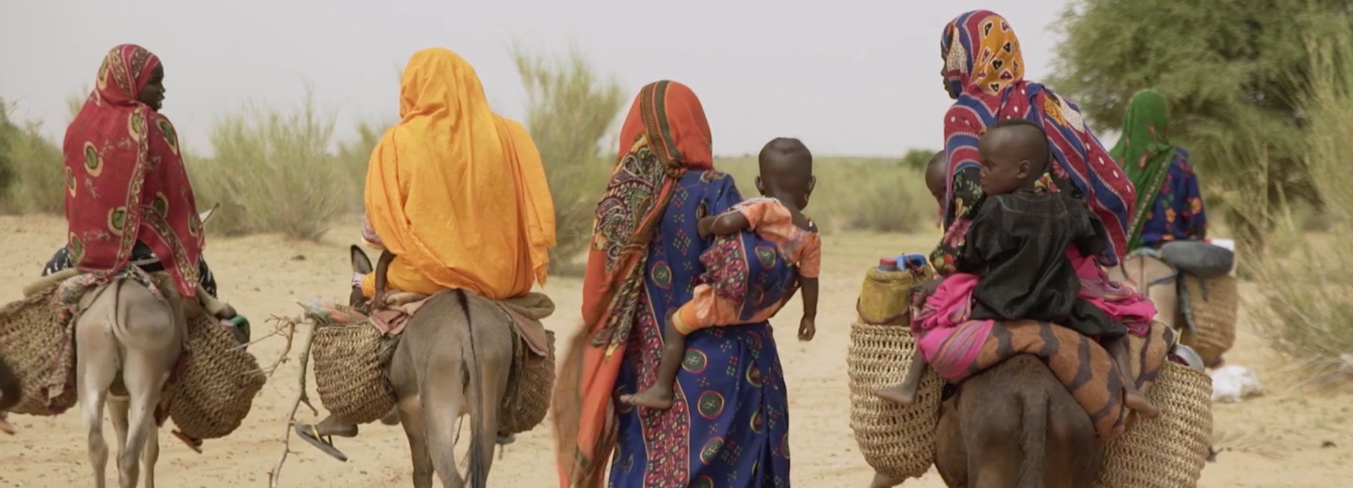 Frauen im Tschad laufen durch den Sand.