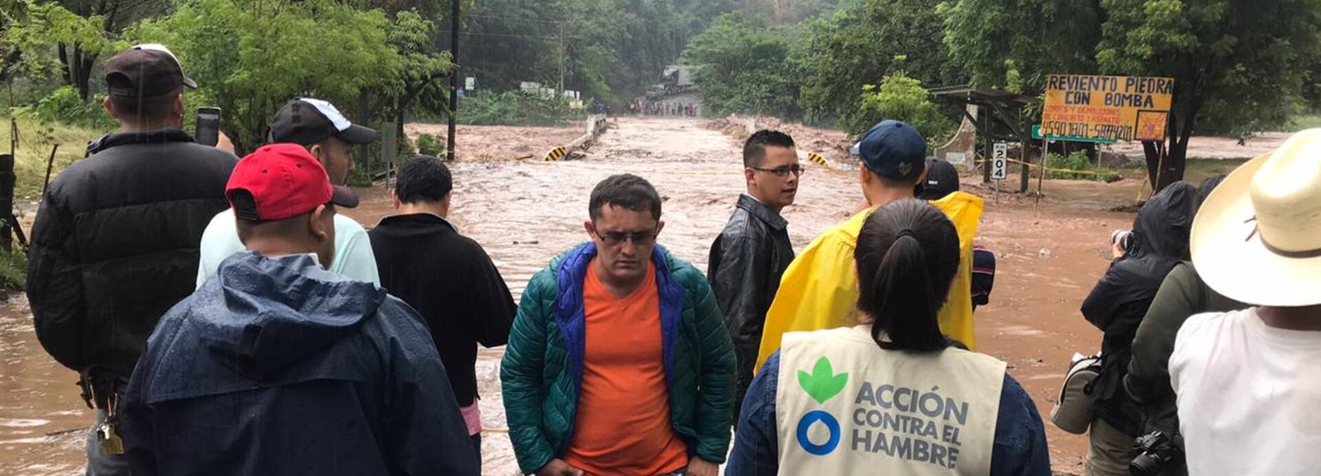 Mitarbeitende von Aktion gegen den Hunger stehen vor einer vom Sturm Iota zerstörten Brücke.