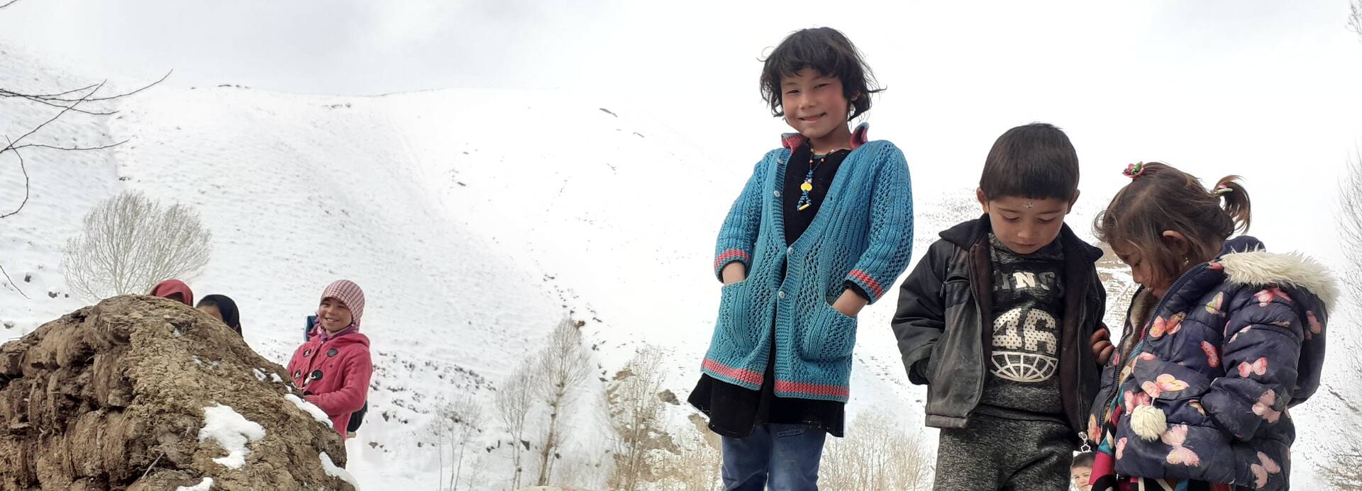 Kinder stehen auf einem schneebedecktem Hügel