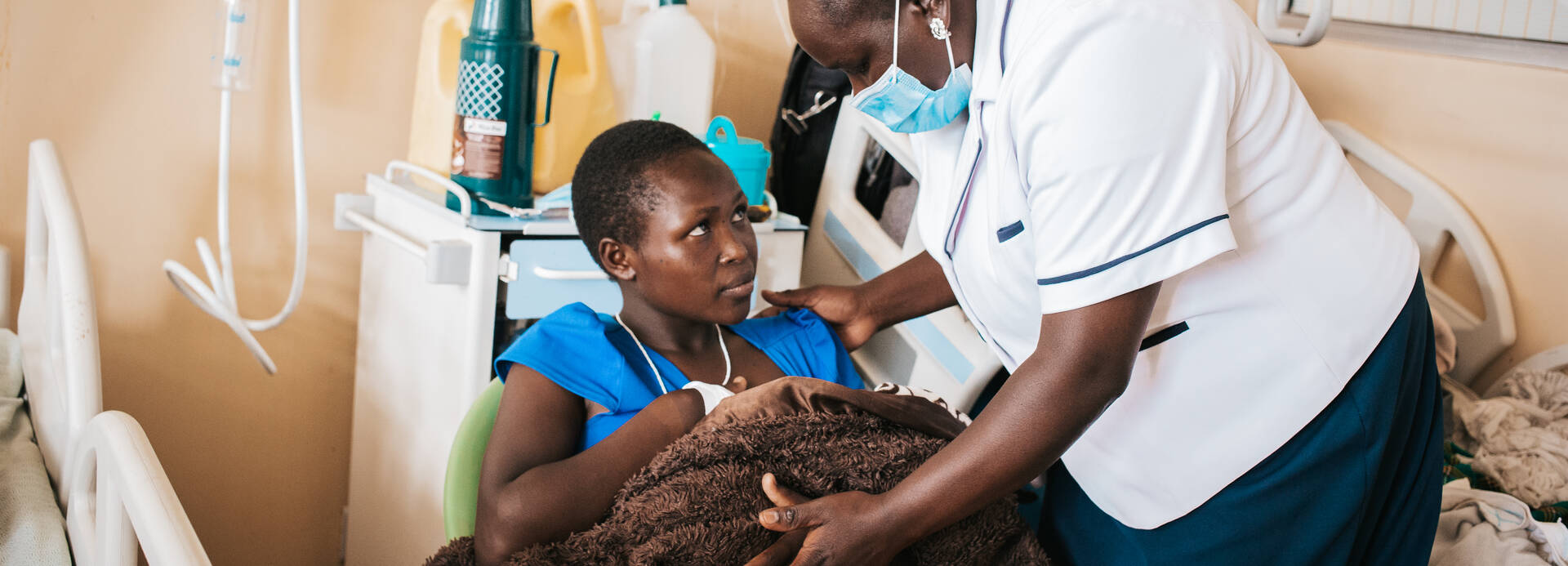 Mitarbeiterin von Aktion gegen den Hunger hilft Mutter und Kind im Stillraum in Kenia Mitarbeiterin von Aktion gegen den Hunger hilft Mutter und Kind im Stillraum in Kenia