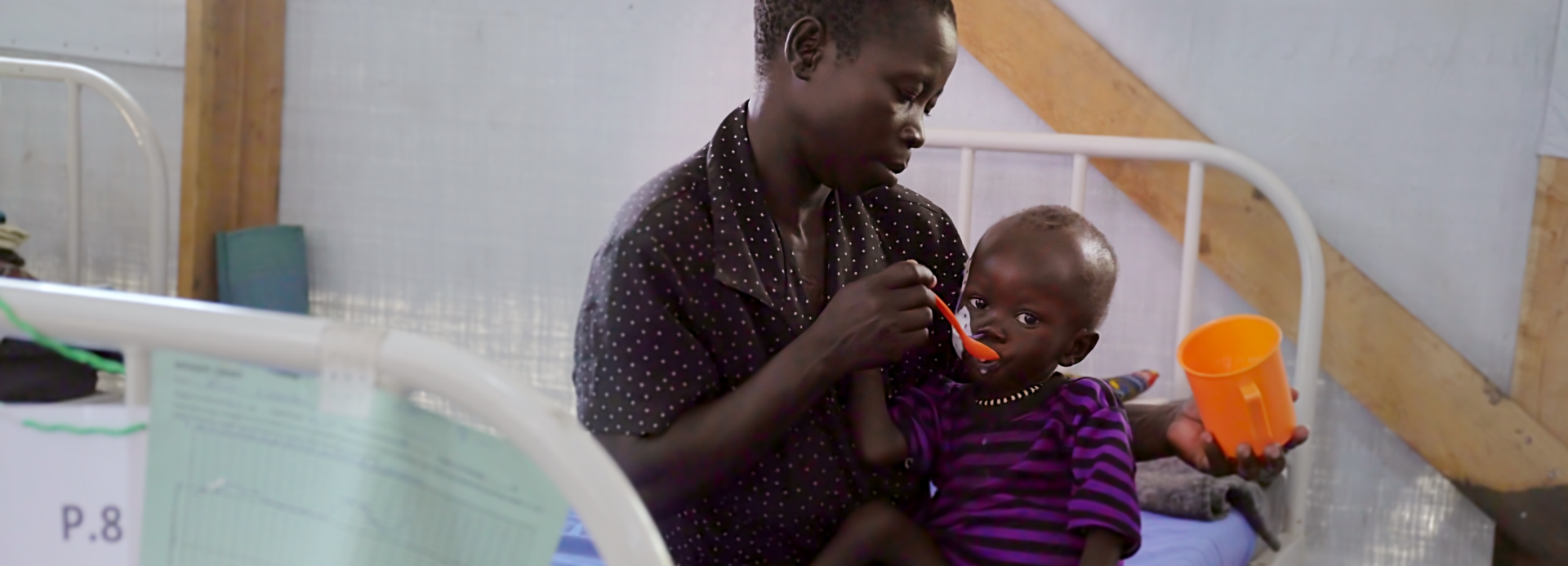 Mutter füttert mangelernährtes Kind in einer Gesundheitsstation von Aktion gegen den Hunger.
